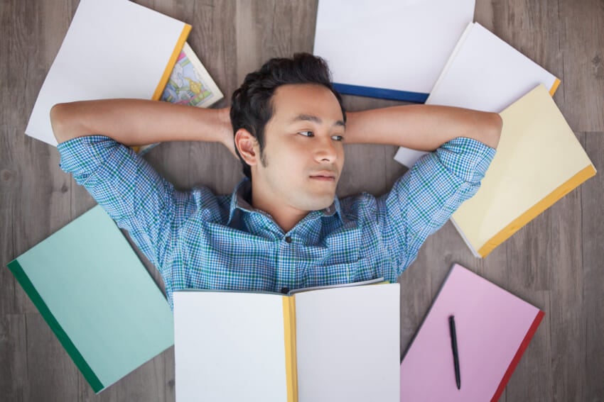 Pensive-asian-guy-resting-floor-with-books.jpg