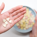Close-up-of-woman-hold-heart-shaped-vitamins-or-mineral-pills-on-palm-blurred-hand-holding-bowl-of-colored-vitamins.jpg
