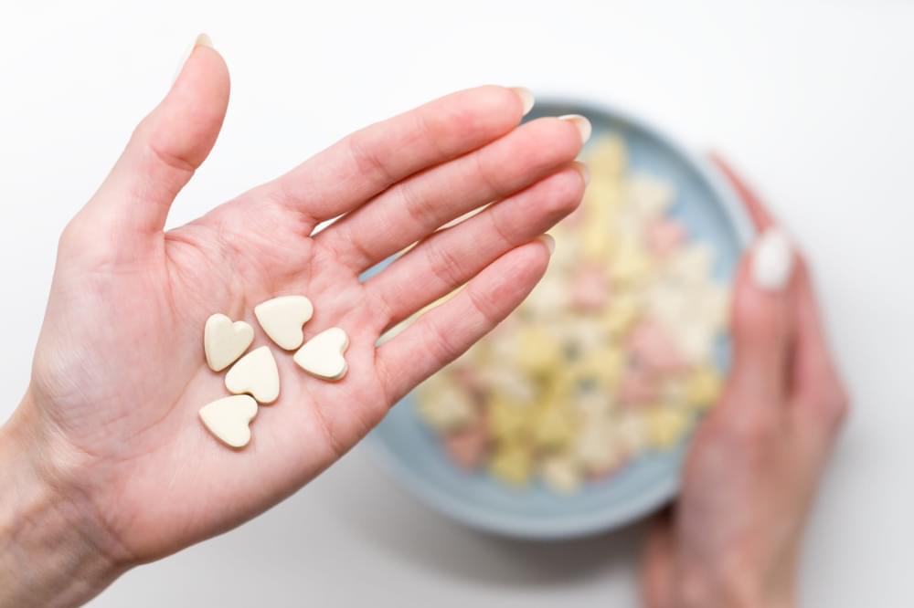 Close-up-of-woman-hold-heart-shaped-vitamins-or-mineral-pills-on-palm-blurred-hand-holding-bowl-of-colored-vitamins.jpg