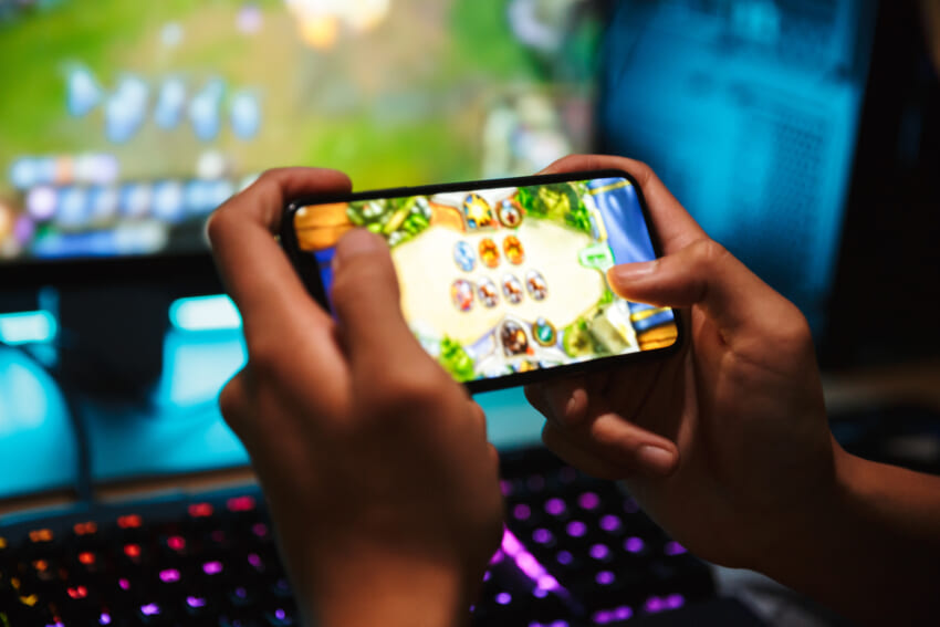 Hands-young-gamer-boy-playing-video-games-smartphone-computer-dark-room-wearing-headphones-using-backlit-colorful-keyboard.jpg