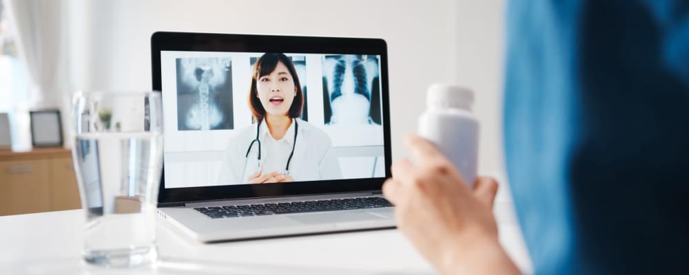 Young-asia-lady-using-computer-laptop-talk-about-disease-video-conference-call-with-senior-doctor-online-consultation-living-room-home.jpg