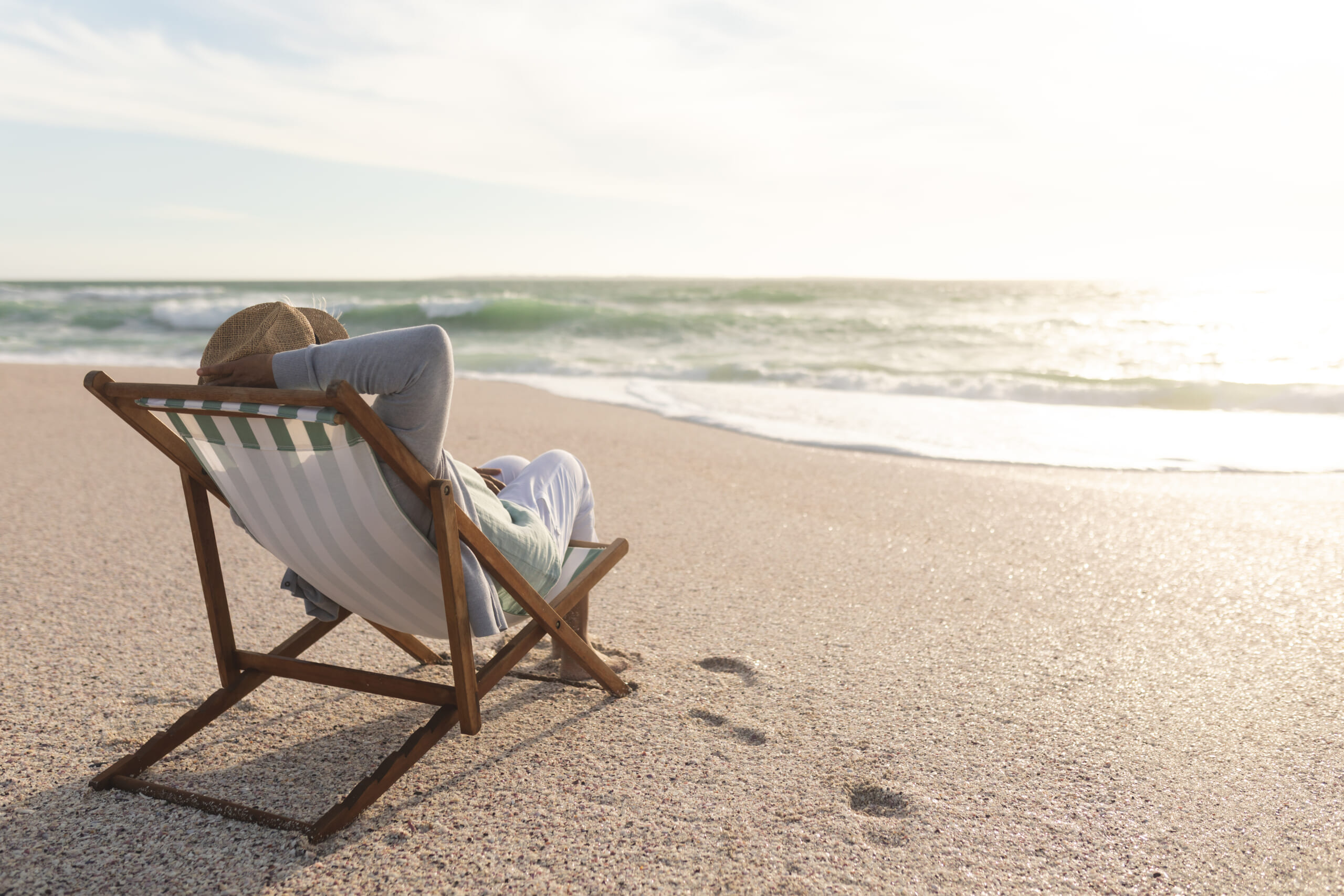 Relaxed-retired-senior-biracial-woman-sitting-folding-chair-enjoying-sunset-beach-lifestyle-weekend.jpg
